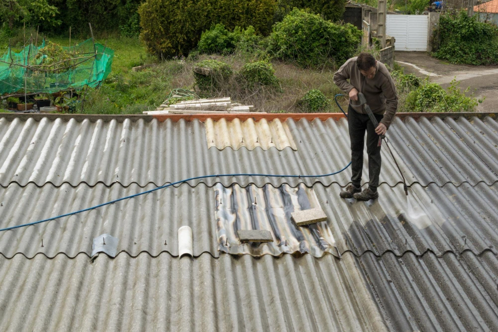 Professional pressure washing of a corrugated metal roof to remove debris.