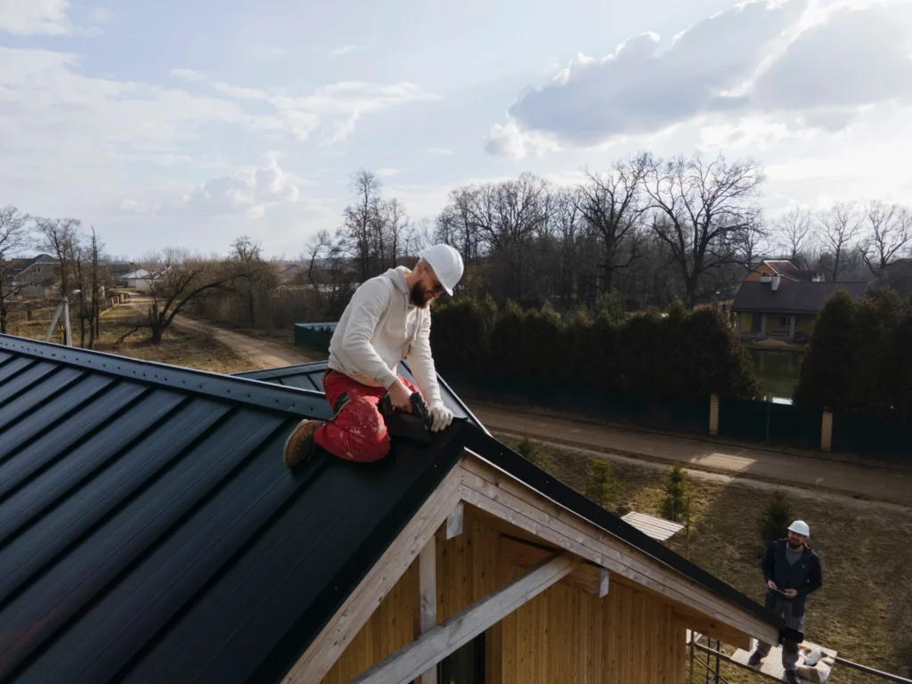 Roof maintenance technician repairing tiles on a pitched building roof.