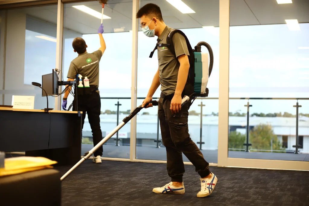 Professional cleaner vacuuming office carpets to remove dust and allergens.