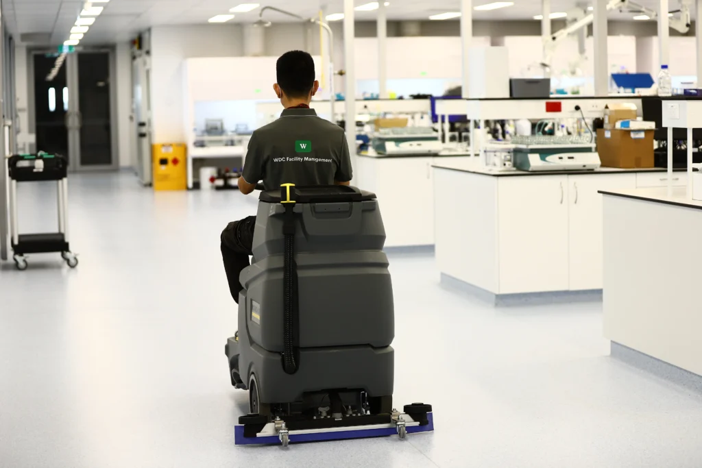 Rear view of an industrial floor cleaning machine polishing vinyl floors in a research facility.