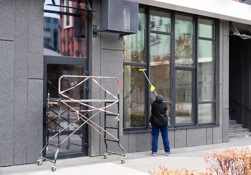 Exterior window cleaner working on scaffolding to clean modern office building glass.