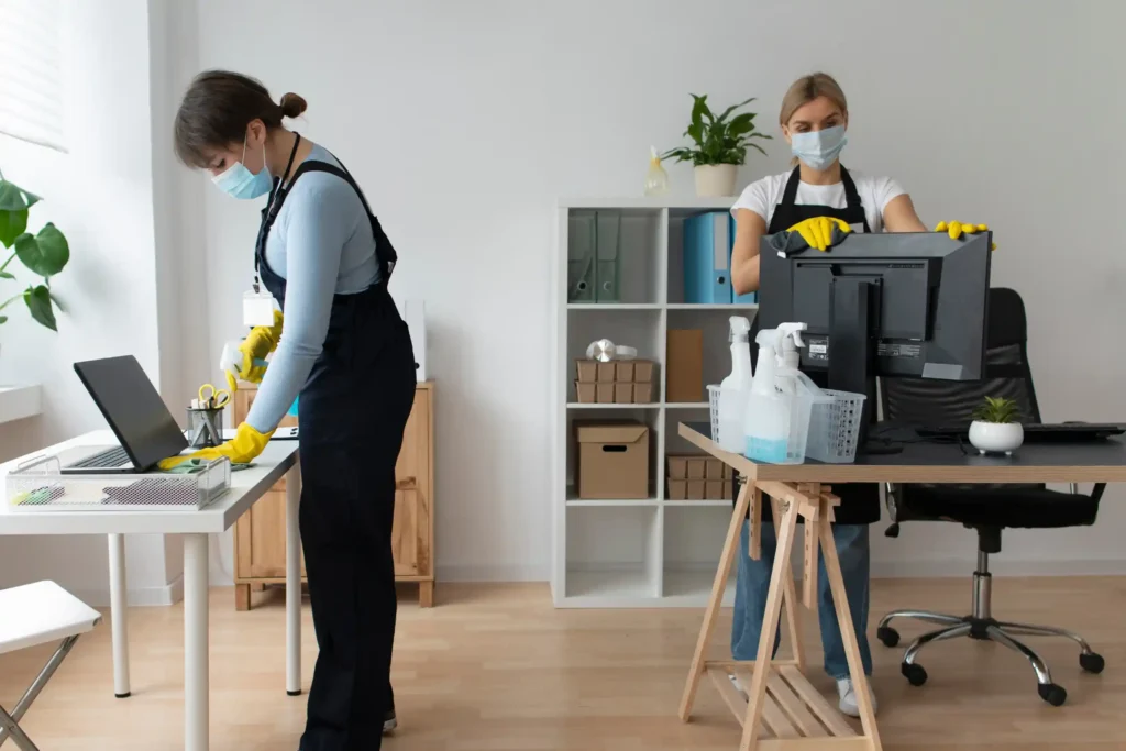 Office cleaner wiping dust from shelving units in a corporate workspace.