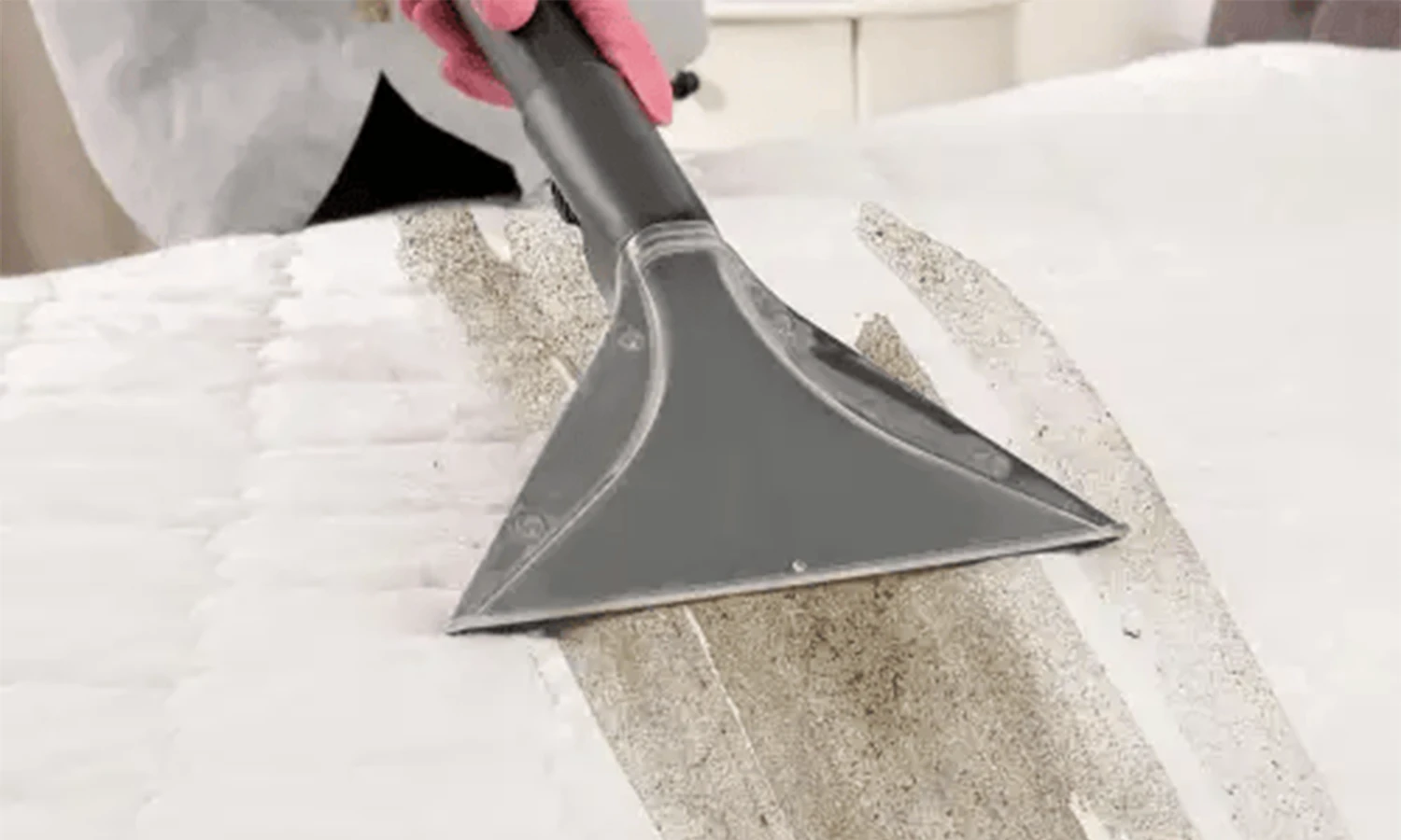 before-2 Close-up of a steam cleaning nozzle extracting dirt from a beige fabric couch.